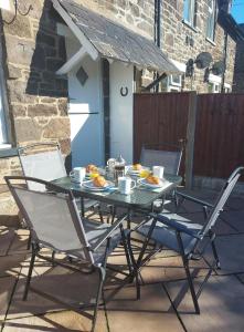einen Tisch und Stühle auf einer Terrasse mit Essen drauf in der Unterkunft Railway Cottage in Conwy