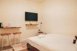 a bedroom with a bed and a tv on the wall at Juran B&B in Nanwan