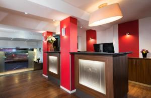 a bar in a room with red walls at Leonardo Hotel Frankfurt City Center in Frankfurt/Main