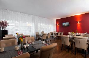 a restaurant with tables and chairs and a red wall at Leonardo Hotel Frankfurt City Center in Frankfurt
