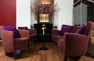 a waiting room with purple chairs and a table at Leonardo Hotel Frankfurt City Center in Frankfurt