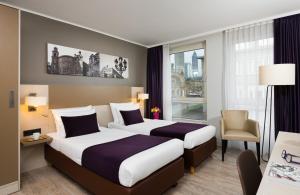 a hotel room with two beds and a window at Leonardo Hotel Frankfurt City Center in Frankfurt