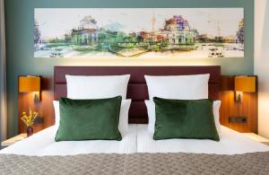 a bedroom with a bed with two green pillows at Leonardo Royal Hotel Berlin Alexanderplatz in Berlin