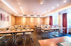 uma sala de aula vazia com mesas e cadeiras num quarto em Leonardo Hotel Düsseldorf City Center em Dusseldorf