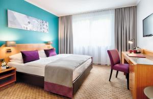 a hotel room with a bed and a desk at Leonardo Hotel Düsseldorf City Center in Düsseldorf
