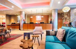 a lobby with a blue couch and a waiting room at Leonardo Royal Hotel Düsseldorf Königsallee in Düsseldorf