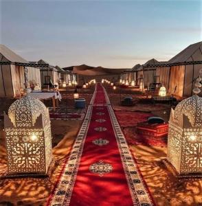 um quarto com tapete vermelho e fileiras de tendas em Sahara Luxury Tented Camp em Merzouga