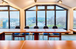 una sala de conferencias con mesas, sillas y ventanas grandes en Leonardo Hotel Hamburg Elbbrücken, en Hamburgo