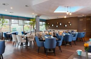a dining room with blue chairs and tables at Leonardo Royal Hotel Frankfurt in Frankfurt
