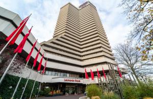 a building with red flags in front of it at Leonardo Royal Hotel Frankfurt in Frankfurt