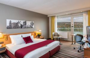 pokój hotelowy z łóżkiem i dużym oknem w obiekcie Leonardo Royal Hotel Frankfurt w Frankfurcie nad Menem