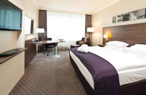 um quarto de hotel com uma cama grande e uma secretária em Leonardo Royal Hotel Düsseldorf Königsallee em Dusseldorf
