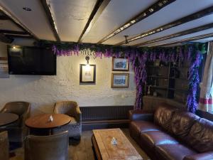 Litherland的住宿－Jubilee pub，酒吧配有皮沙发、桌子和电视
