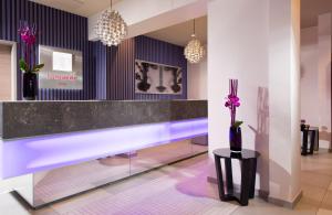 a lobby with a purple counter and a vase with purple flowers at Leonardo Hotel Munich City Olympiapark in Munich