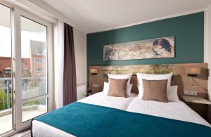 ein Schlafzimmer mit einem großen Bett und einem großen Fenster in der Unterkunft Leonardo Hotel Munich City Olympiapark in München