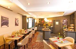 ein Restaurant mit Tischen und Stühlen und eine Küche in der Unterkunft Leonardo Hotel Munich City North in München