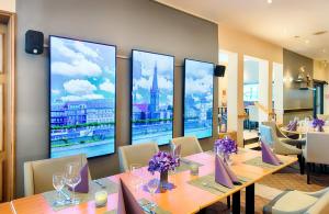 a restaurant with tables and chairs and large windows at Leonardo Hotel Düsseldorf Airport Ratingen in Ratingen