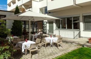 a patio with tables and chairs with an umbrella at Leonardo Hotel Munich City North in Munich