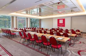 una sala de conferencias con mesas y sillas rojas. en Leonardo Hotel Frankfurt City South en Frankfurt