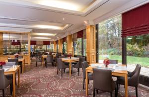 ein Restaurant mit Tischen und Stühlen und großen Fenstern in der Unterkunft Leonardo Hotel Frankfurt City South in Frankfurt am Main