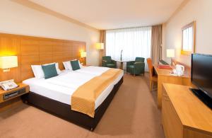 a hotel room with a large bed and a flat screen tv at Leonardo Hotel Heidelberg Walldorf in Walldorf