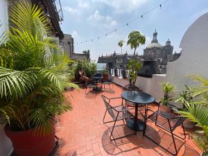 eine Terrasse mit Stühlen, Tischen und Topfpflanzen in der Unterkunft Hostel Mundo Joven Catedral in Mexiko-Stadt