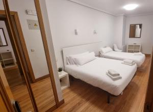 two beds in a small room with a mirror at Pension Ipar in Zarautz