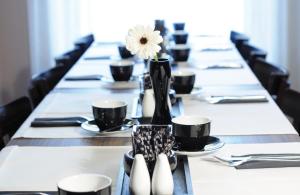 ミュンヘンにあるレオナルド ブティック ホテル ミュンヘンの長いテーブルと黒い椅子、花瓶の白い花