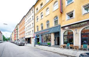 a city street with buildings with tables and chairs at Leonardo Boutique Hotel Munich in Munich