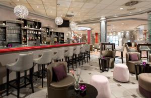 un bar con una fila di sgabelli in un ristorante di Leonardo Hotel Köln a Colonia
