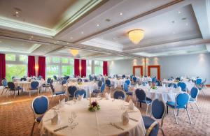 ハイデルベルクにあるレオナルド ホテル ハイデルベルクの白いテーブルと青い椅子が備わる宴会場