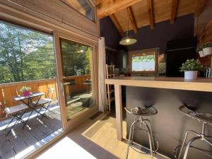 a kitchen with a bar and a balcony with a table and chairs at Chalet le petit Nicolas, jacuzzi, vue Mont Blanc in Chamonix-Mont-Blanc