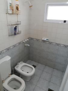 a white bathroom with a toilet and a window at (12 pers. o +) Casa quinta con pileta sobre el río PRECIO DOLAR BILLETE in Santa Fe