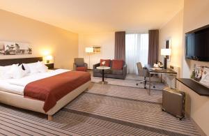 um quarto de hotel com uma cama, uma secretária e uma televisão em Leonardo Hotel Hannover Airport em Hanôver