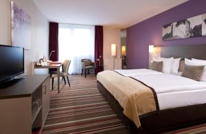 a hotel room with a large bed and a desk at Leonardo Hotel Hannover Airport in Hannover