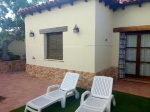 duas cadeiras brancas sentadas em frente a uma casa em 3 bedrooms villa with private pool and furnished terrace at Las Casas em Las Casas