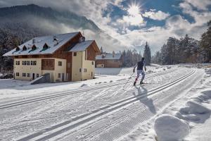 a man is cross country skiing in front of a building at Natura Boutique Chalet Wellness SPA in Dobbiaco