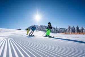 three people are skiing down a snow covered slope at Pension Linder in Seeboden