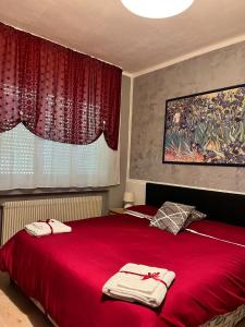 a bedroom with a red bed with two towels on it at Albergo Meridiana in Pergine Valsugana