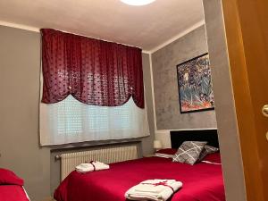 a bedroom with a red bed and a window at Albergo Meridiana in Pergine Valsugana