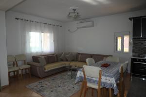 Villa Çerpja في Kamëz: غرفة معيشة مع أريكة وطاولة وكراسي