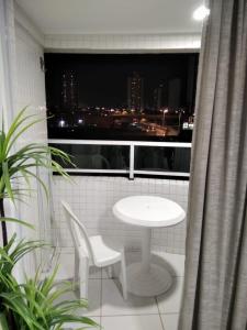 una mesa blanca y sillas en un balcón con ventana en Apartamento em Nova Betânia - West Flat Mossoró, en Mossoró