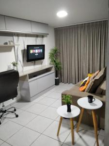 a living room with a couch and a tv and two tables at Apartamento em Nova Betânia - West Flat Mossoró in Mossoró