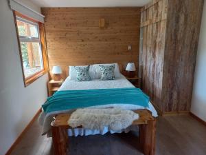 sypialnia z łóżkiem z drewnianą ścianą w obiekcie Cabañas Chaya Mapu w mieście Puerto Aisén