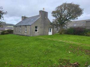 an old house with a grass yard in front of it at Kirbister Mill Farm Cottage in Kirkwall