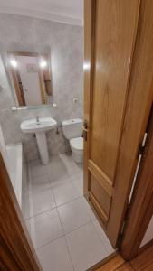a bathroom with a toilet and a sink and a door at Pension Ipar in Zarautz
