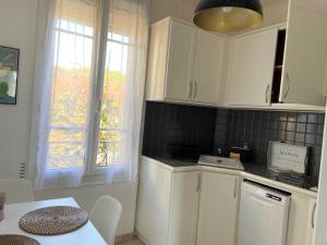 a kitchen with white cabinets and a table and a window at Superbe Appartement de 45m² à Antony in Antony