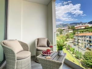 un balcone con 2 sedie, un tavolo e una finestra di Uptown Apartment by LovelyStay a Funchal