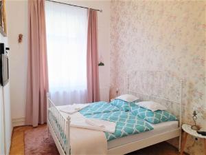 Un dormitorio con una cama blanca con sábanas azules y una ventana en D16 Apartman, en Szentgotthárd