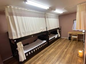 2 łóżka piętrowe w pokoju z drewnianą podłogą w obiekcie Bonfire Hostel Osaka w Osace